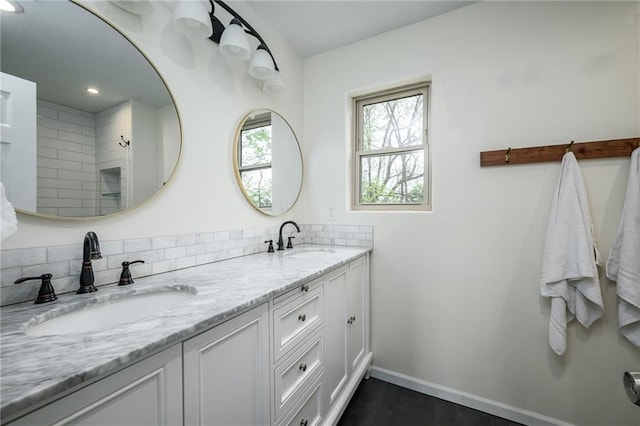 bathroom with double vanity, baseboards, a sink, and tile patterned flooring