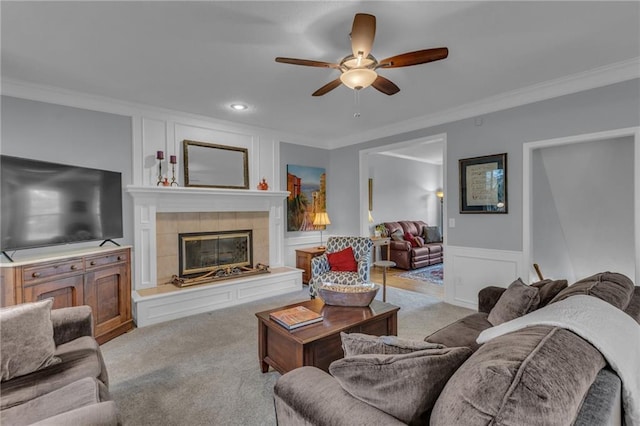 carpeted living room with ornamental molding, a decorative wall, recessed lighting, a tile fireplace, and a ceiling fan