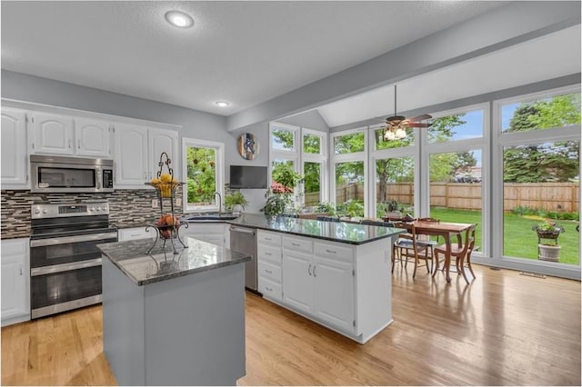 kitchen featuring decorative backsplash, a peninsula, white cabinets, a sink, and appliances with stainless steel finishes