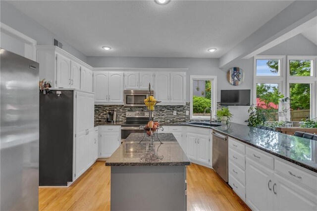 kitchen featuring dark stone counters, backsplash, appliances with stainless steel finishes, and a sink