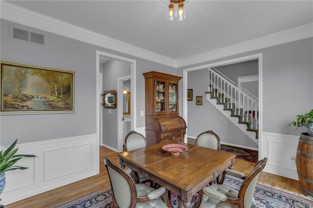 dining space with stairway, a wainscoted wall, light wood finished floors, and visible vents