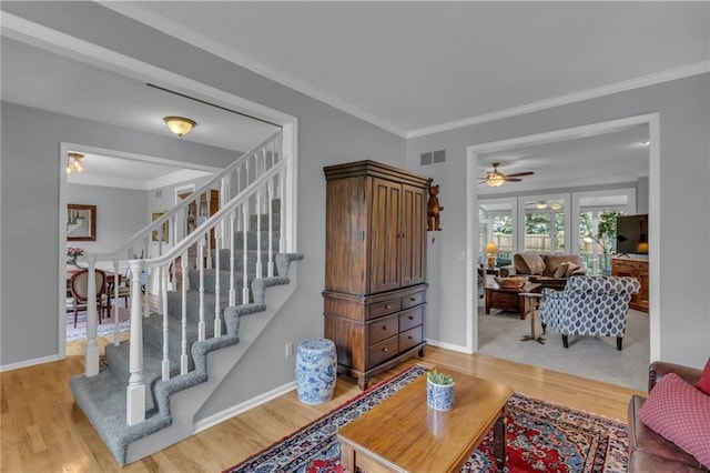 living room featuring stairs, visible vents, ornamental molding, and wood finished floors