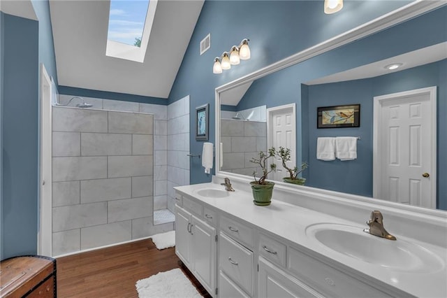 full bathroom with a walk in shower, visible vents, a sink, and lofted ceiling with skylight