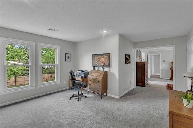 carpeted home office featuring a textured ceiling, baseboards, and visible vents