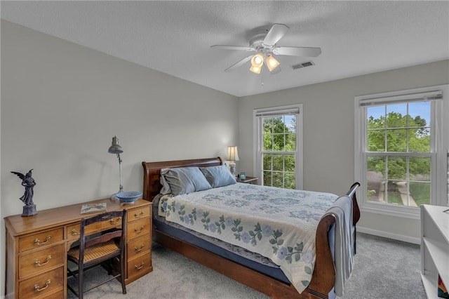 bedroom featuring a ceiling fan, a textured ceiling, visible vents, baseboards, and carpet flooring