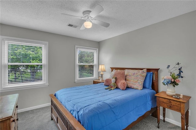 carpeted bedroom featuring baseboards, multiple windows, ceiling fan, and visible vents
