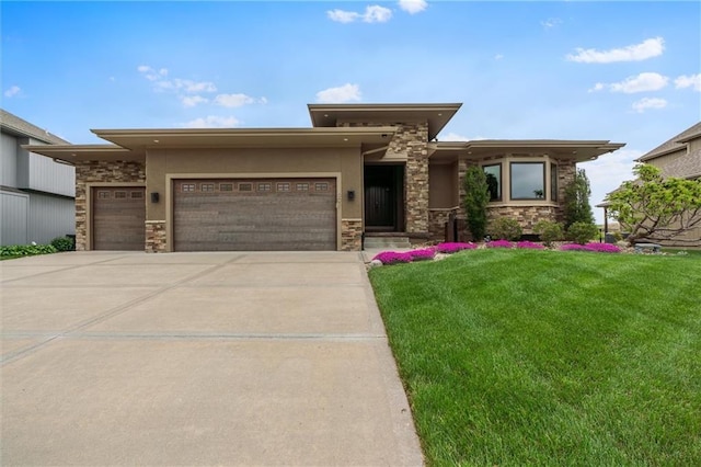 prairie-style home with concrete driveway, a front yard, an attached garage, and stone siding