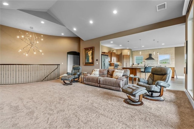living area featuring an inviting chandelier, carpet floors, lofted ceiling, and visible vents