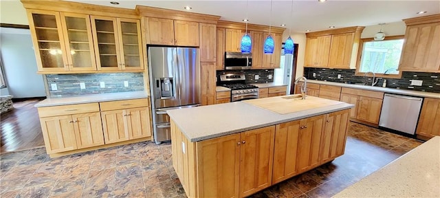 1620 Neosho St, Humboldt, KS 66748 - kitchen featuring an island with sink, decorative backsplash, appliances with stainless steel finishes, light countertops, and a sink