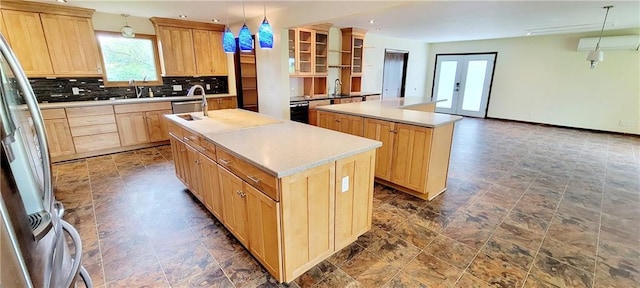 1620 Neosho St, Humboldt, KS 66748 - kitchen featuring open shelves, stone finish flooring, light brown cabinets, a kitchen island with sink, and backsplash