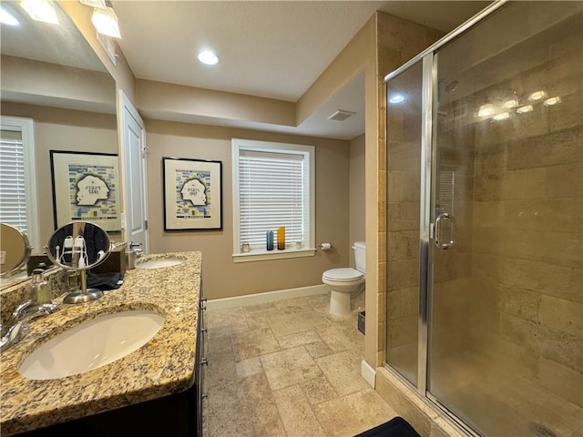 bathroom featuring baseboards, a sink, a stall shower, and stone tile floors