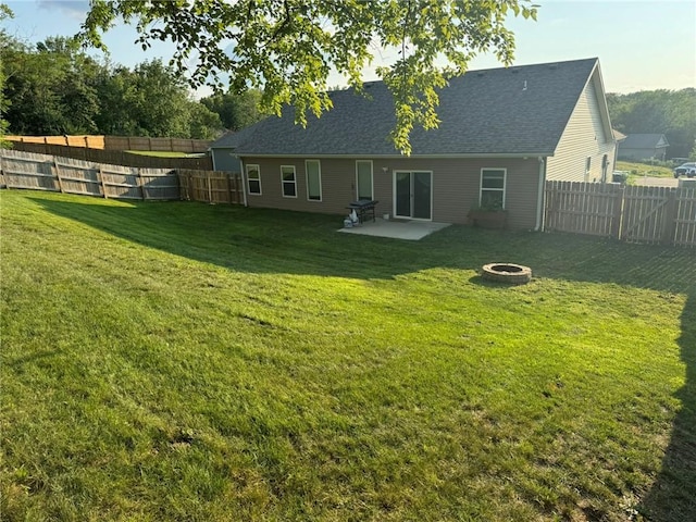 rear view of property featuring a lawn, a fire pit, a patio area, and a fenced backyard