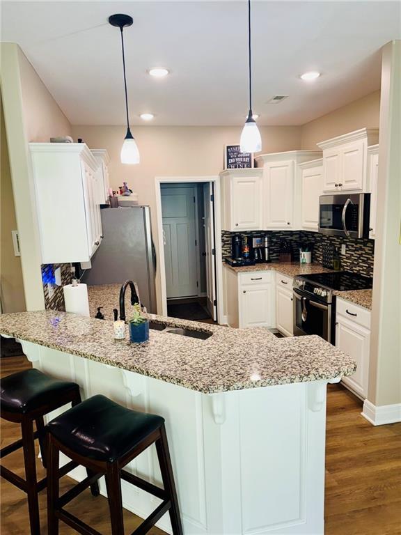 kitchen featuring a breakfast bar area, white cabinets, a peninsula, and stainless steel appliances