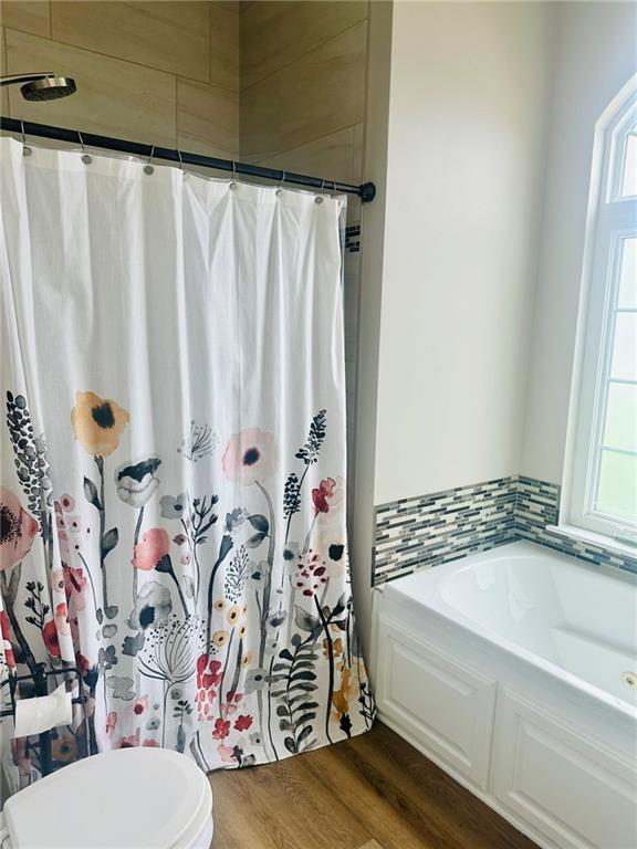 full bath with curtained shower, a bath, toilet, and wood finished floors