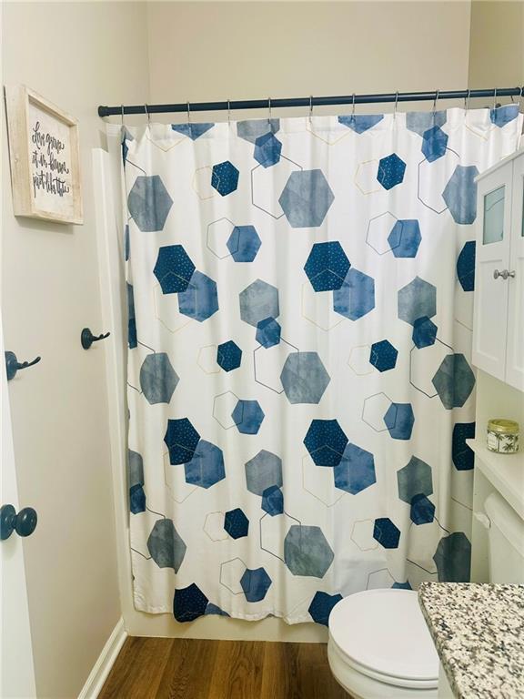 full bathroom with wood finished floors, toilet, and curtained shower