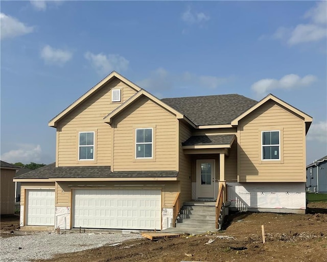 split foyer home with driveway, a garage, and roof with shingles