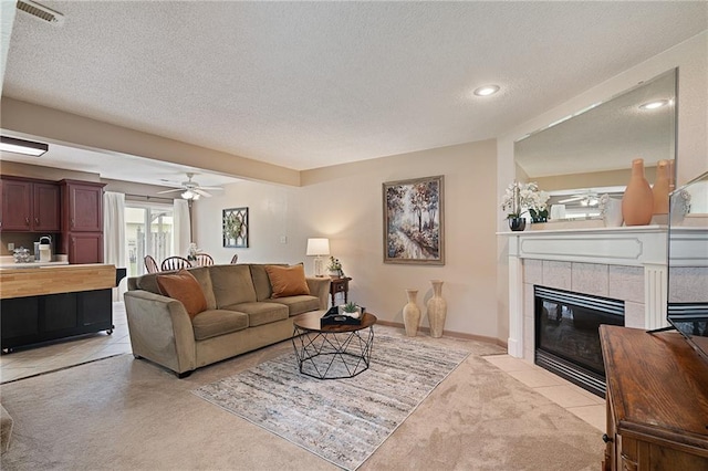 living area with a fireplace, light carpet, recessed lighting, a textured ceiling, and a ceiling fan