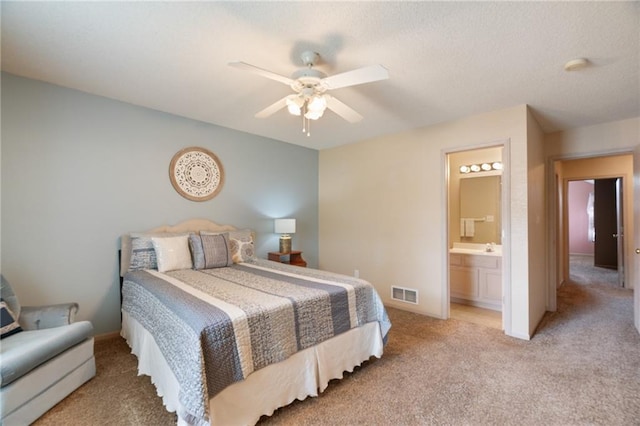 carpeted bedroom featuring ensuite bathroom, a ceiling fan, and visible vents