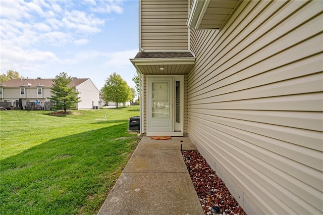 entrance to property with a lawn, central AC unit, and a residential view