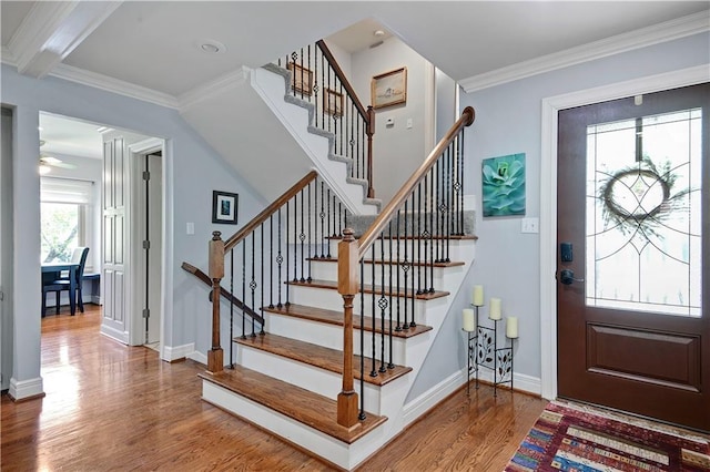 entrance foyer with stairs, crown molding, baseboards, and wood finished floors