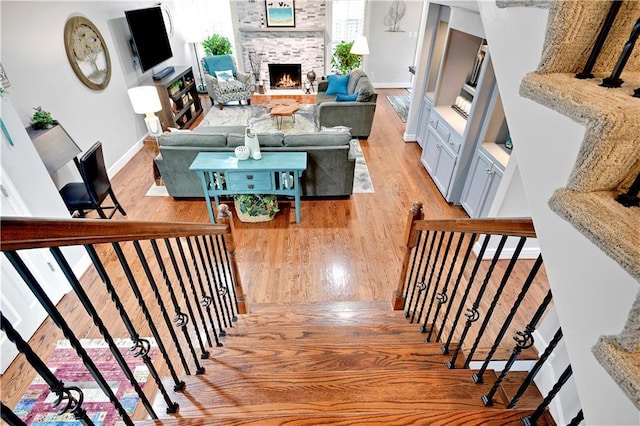 stairs featuring baseboards, wood finished floors, and a fireplace