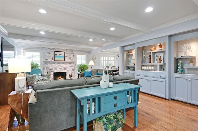 living room with crown molding, beamed ceiling, light wood-style flooring, and a fireplace