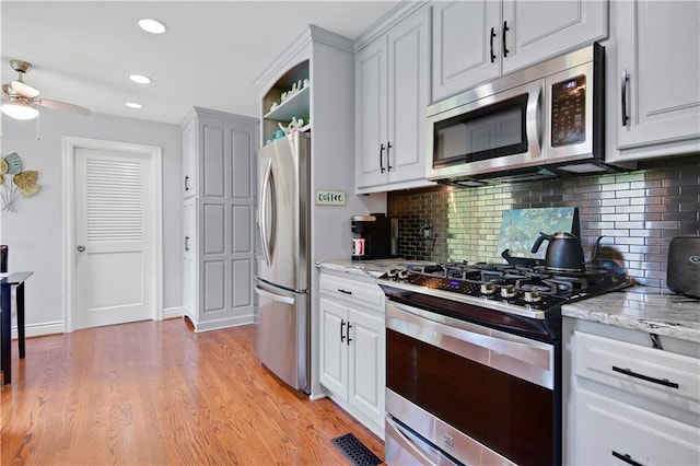 kitchen featuring recessed lighting, tasteful backsplash, a ceiling fan, light wood-style flooring, and appliances with stainless steel finishes