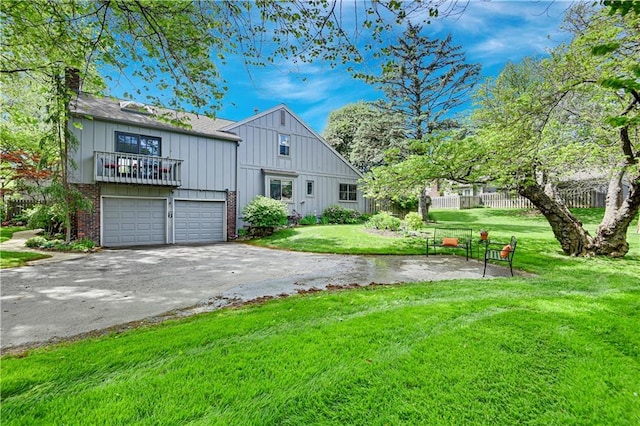 view of front of house featuring board and batten siding, aphalt driveway, brick siding, a front lawn, and an attached garage