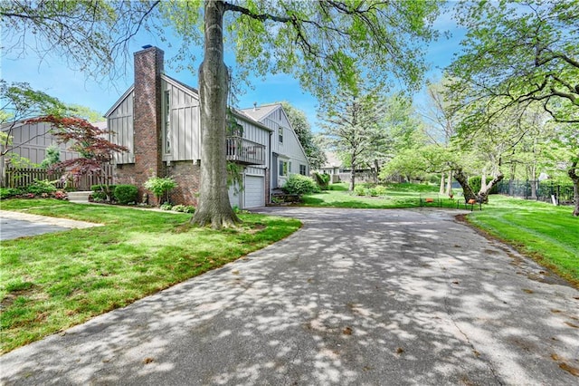 4300 W 112th Ter, Leawood, KS 66211 - view of property exterior featuring driveway, board and batten siding, a garage, a chimney, and a balcony