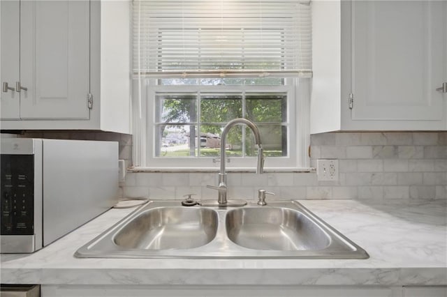 5900 Westridge Rd, Kansas City, MO 64133 - kitchen view of a sink, white cabinetry, and backsplash
