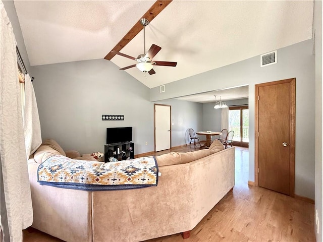 living area featuring a ceiling fan, visible vents, lofted ceiling with beams, and wood finished floors