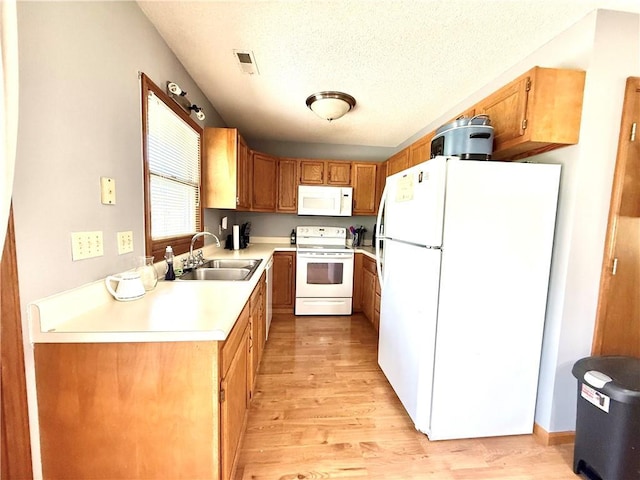 kitchen featuring white appliances, a sink, light wood-style flooring, and light countertops