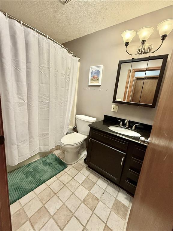 bathroom with toilet, a textured ceiling, a shower with shower curtain, and vanity