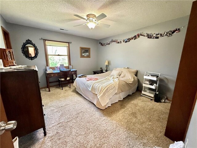 bedroom with visible vents, a textured ceiling, ceiling fan, and light carpet