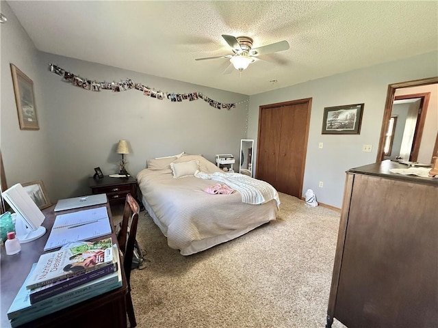 carpeted bedroom with ceiling fan, a closet, and a textured ceiling
