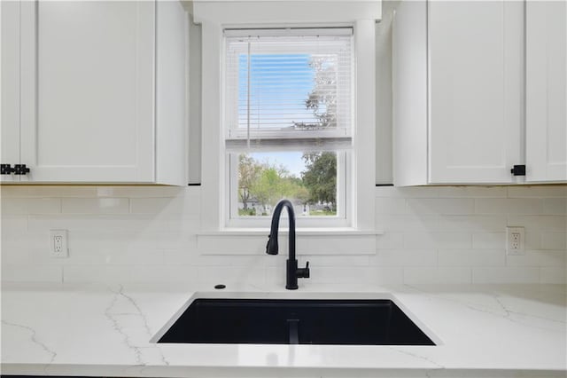 2640 S 53rd St, Kansas City, KS 66106 - kitchen with a sink, a wealth of natural light, backsplash, light stone counters, and white cabinetry