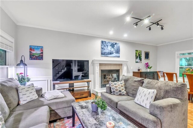 living room with track lighting, ornamental molding, and light wood finished floors