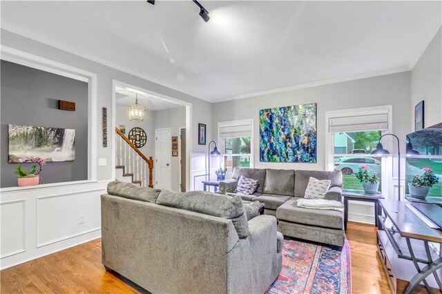 living area with stairs, a chandelier, ornamental molding, and light wood-type flooring