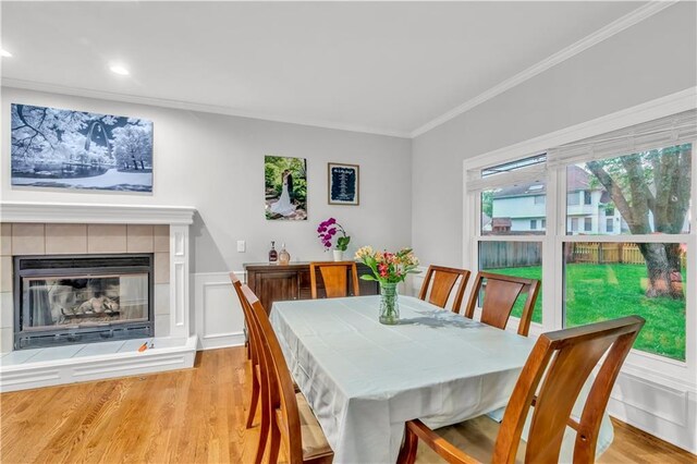 dining space featuring crown molding, recessed lighting, wood finished floors, and a fireplace