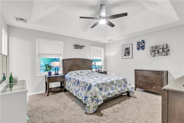 carpeted bedroom featuring baseboards, visible vents, multiple windows, and ceiling fan