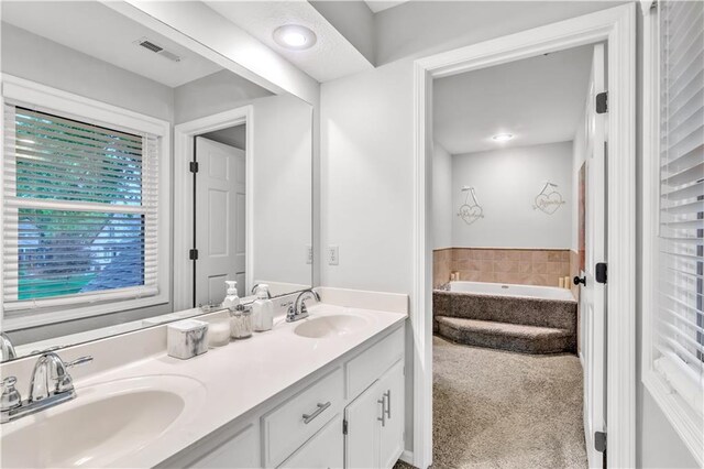 bathroom with visible vents, a sink, a bath, and double vanity