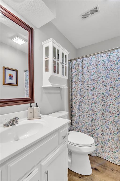 full bathroom featuring visible vents, vanity, wood finished floors, toilet, and a shower with curtain
