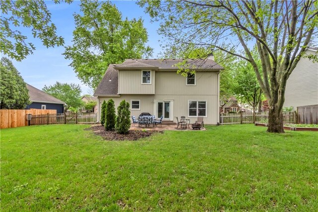 back of house featuring a lawn, a patio, a chimney, and a fenced backyard