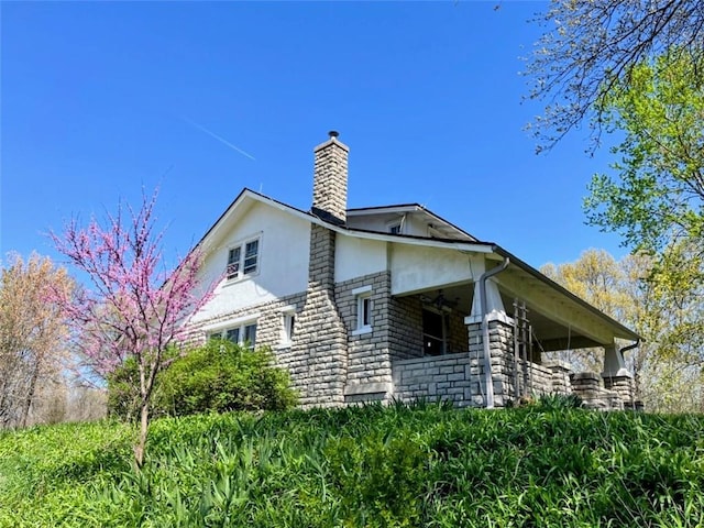 view of property exterior featuring a chimney, stone siding, and stucco siding