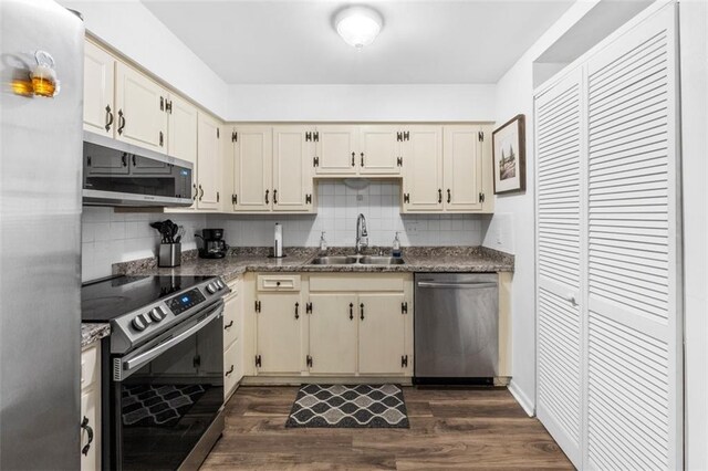 8215 Santa Fe Dr Unit 10, Overland Park, KS 66204 - kitchen with decorative backsplash, dark wood-type flooring, dark stone counters, a sink, and stainless steel appliances