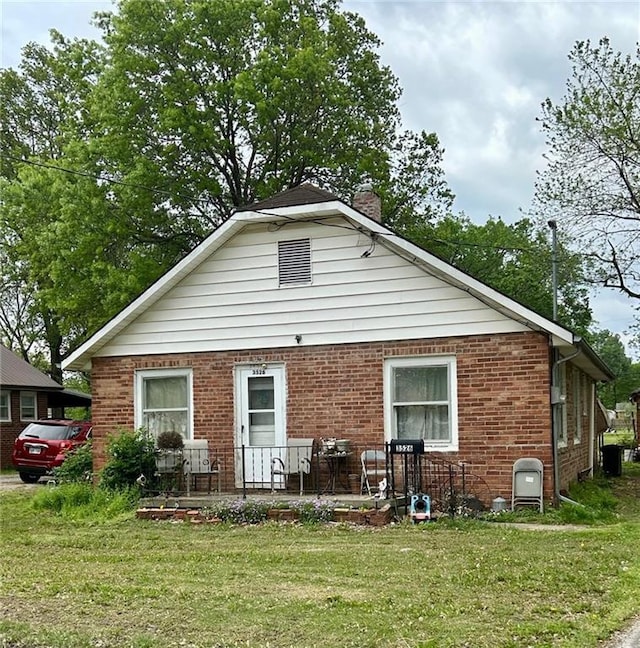 3526 Belmont Ave, Parsons, KS 67357 - back of house with a chimney, a yard, and brick siding