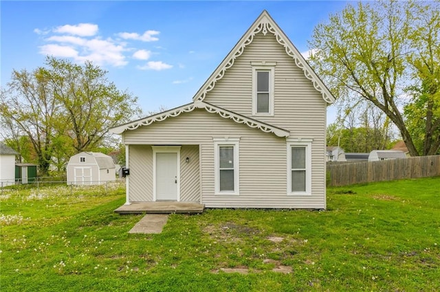back of property with fence, a storage unit, an outdoor structure, and a yard