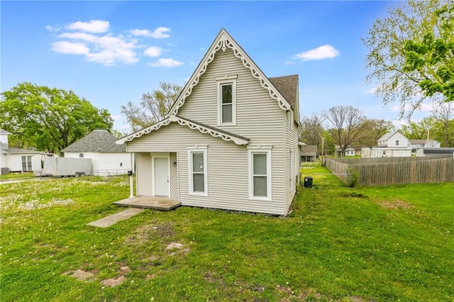 rear view of house with a yard and fence