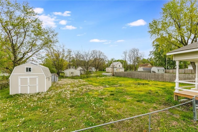 view of yard with fence, an outdoor structure, and a storage unit