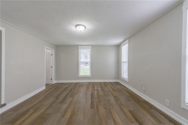 spare room with baseboards, a textured ceiling, and wood finished floors